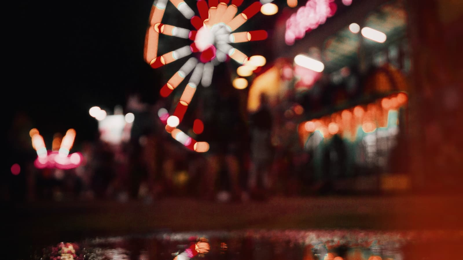 Carnival rides and a Ferris wheel at night